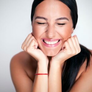 A woman smiling with her hands on the face.